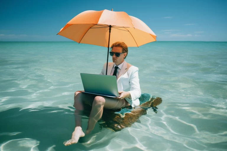 Photographie humoristique d'un homme en costume d'affaires (veste blanche, chemise, cravate, short beige et lunettes de soleil) assis pieds nus dans de l'eau turquoise tropicale sur un petit radeau flottant. Il travaille sur un ordinateur portable argenté sur ses genoux tout en se protégeant du soleil sous un grand parapluie orange vif.